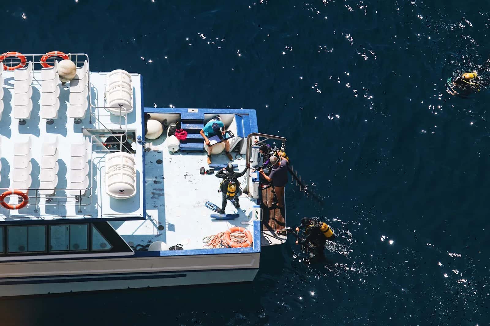 Plongeurs équipés se mettant à l'eau depuis l'arrière d'un bateau de club de plongée, à l'île Maurice