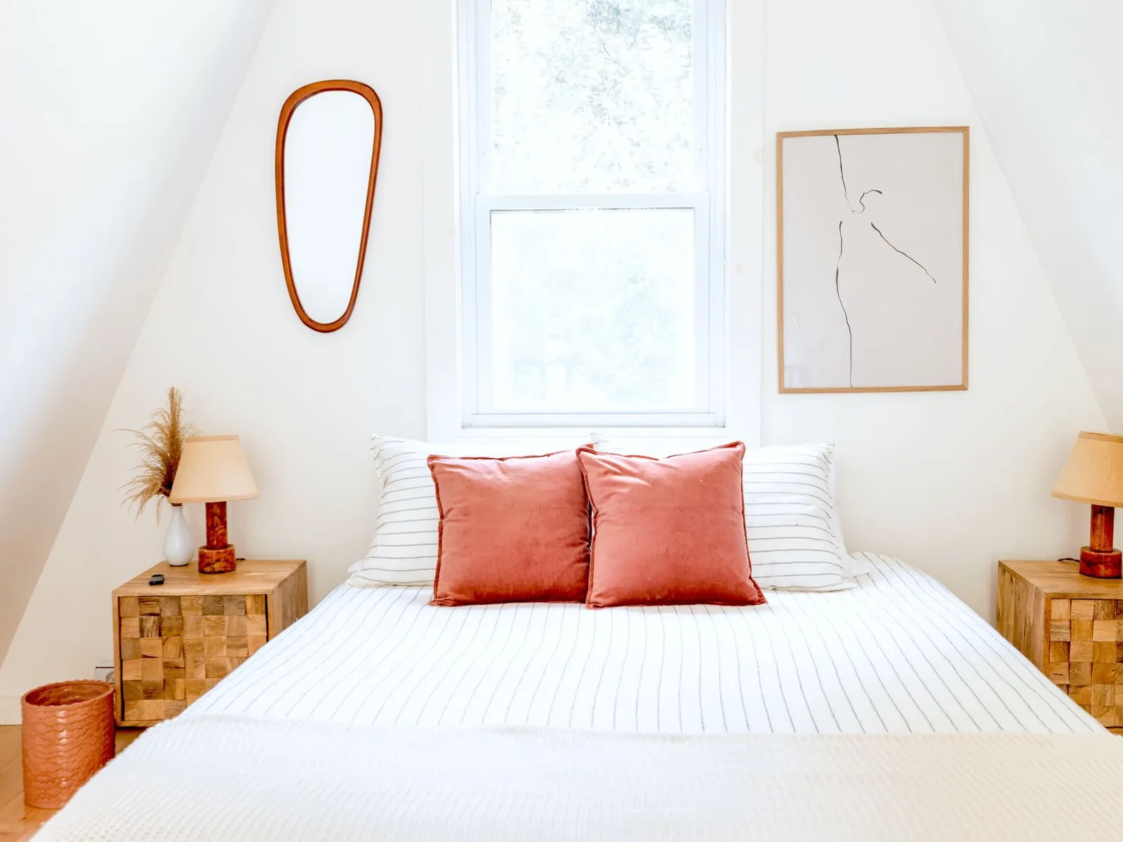 Chambre lumineuse et accueillante, lit blanc, coussins colorés et tables de chevet en bois