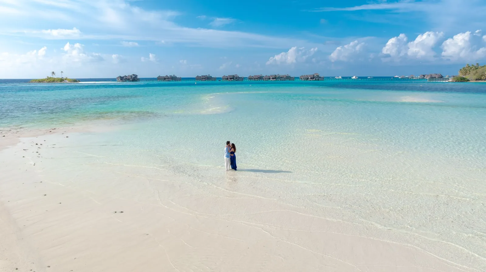 Couple sur une plage de sable blanc au bord d'un lagon turquoise