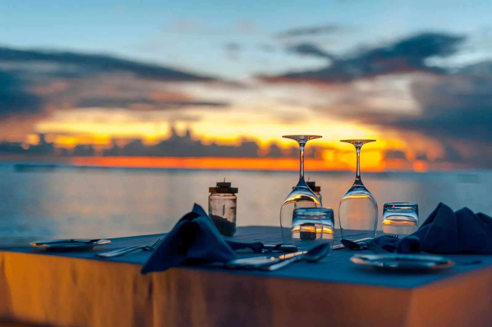 Table de réveillon dressée face à la mer au coucher du soleil, sur la plage d'un resort