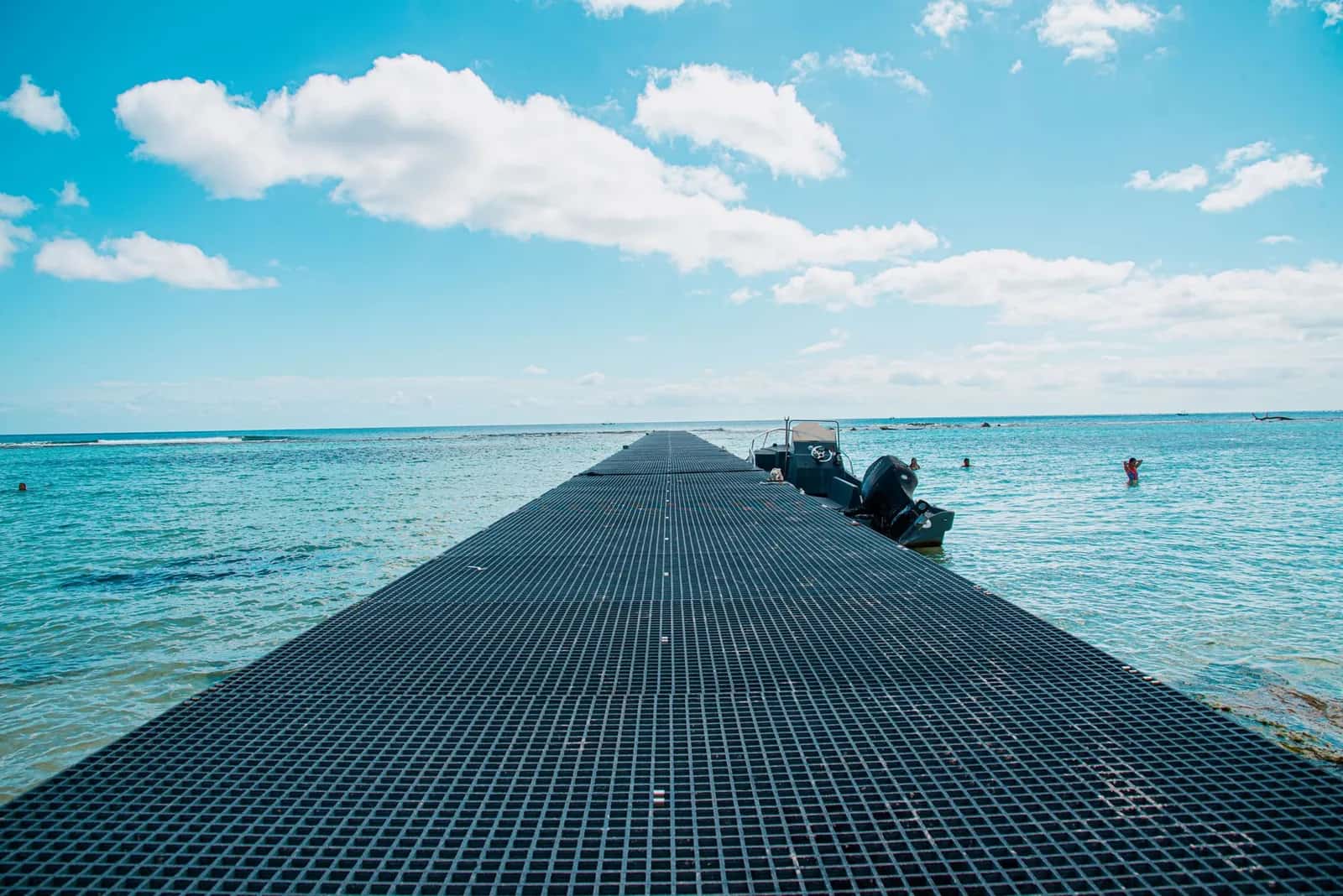 Ponton sur un lagon turquoise avec un bateau à moteur amarré, comme ceux qui partent pour l'île aux Cerfs
