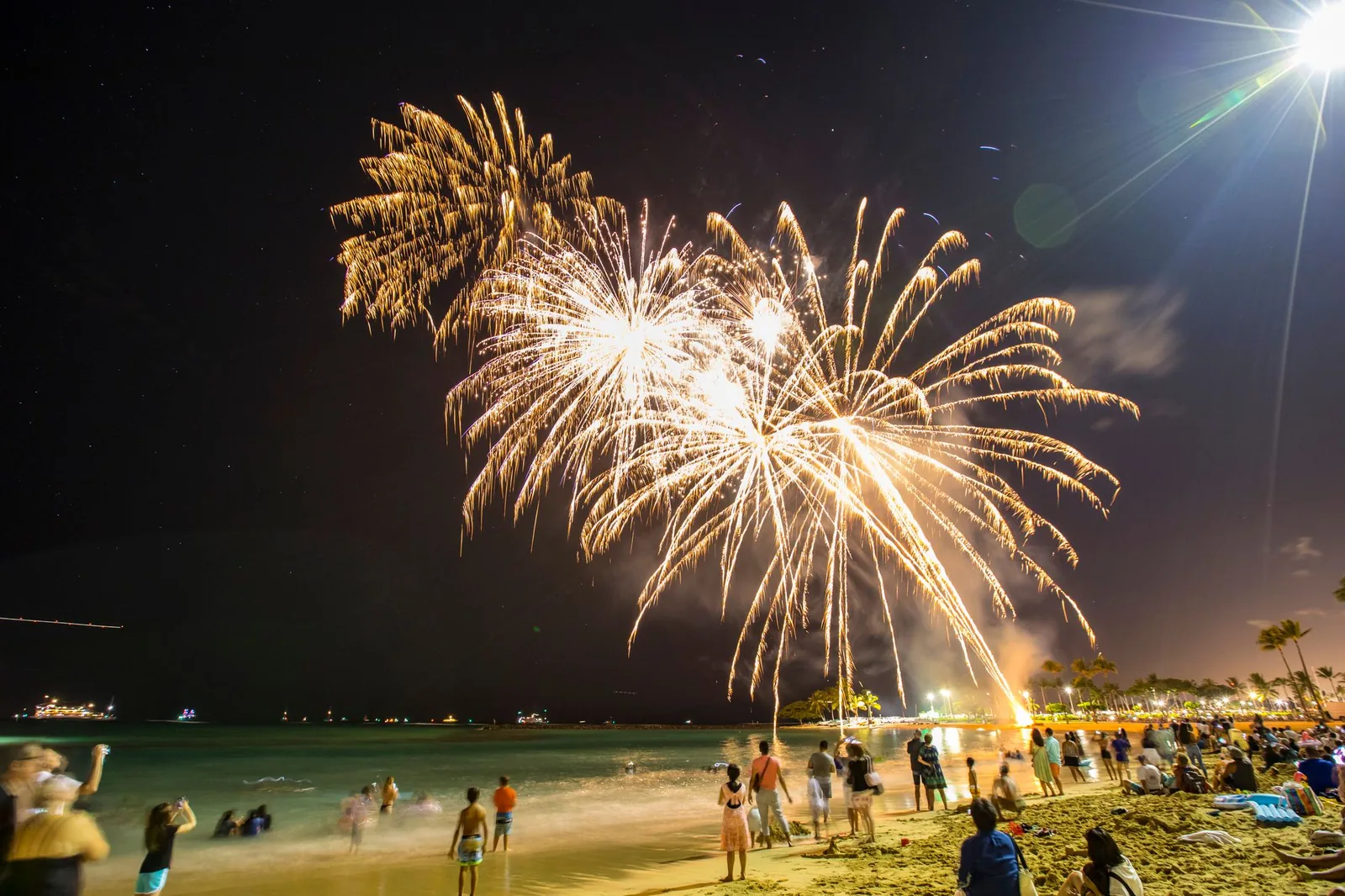 Feux d'artifice dorés au-dessus d'une plage tropicale le soir du Nouvel An