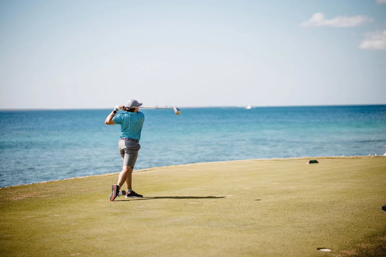 Golfeur sur un green au bord d'un lagon bleu turquoise