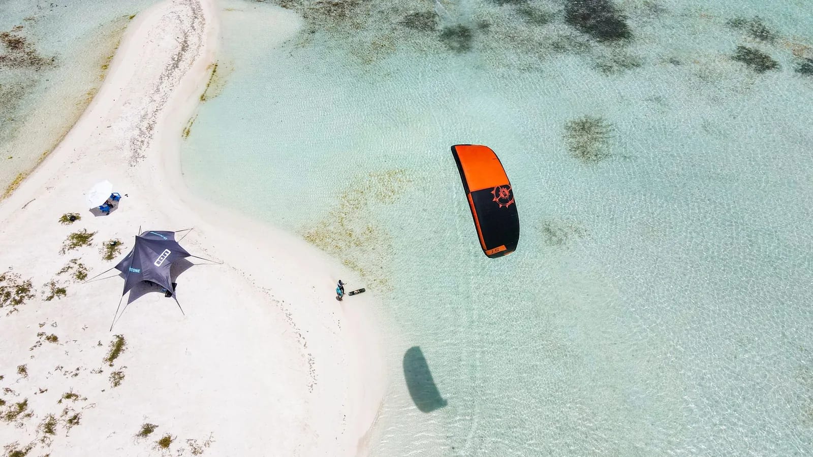 Aile de kitesurf orange au-dessus d'un lagon turquoise peu profond et d'un banc de sable blanc, comme dans les lagons de l'île Maurice