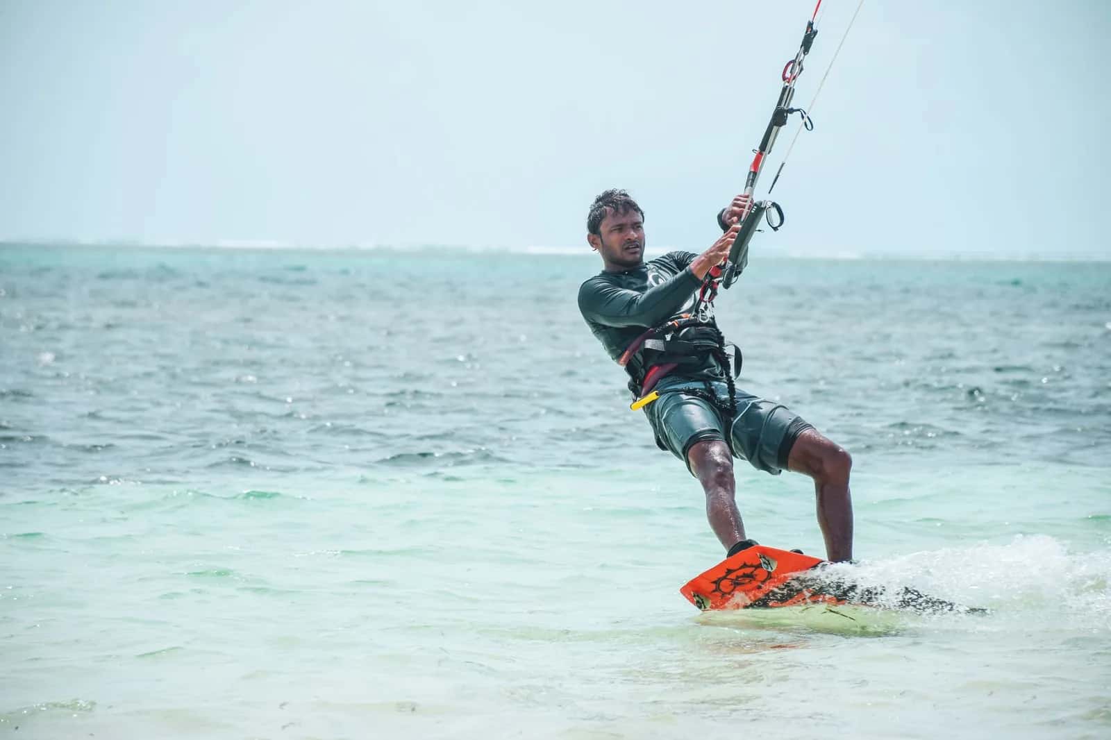 Kitesurfeur sur l'eau claire et peu profonde d'un lagon, récif visible à l'horizon, comme dans le lagon du Morne à l'île Maurice