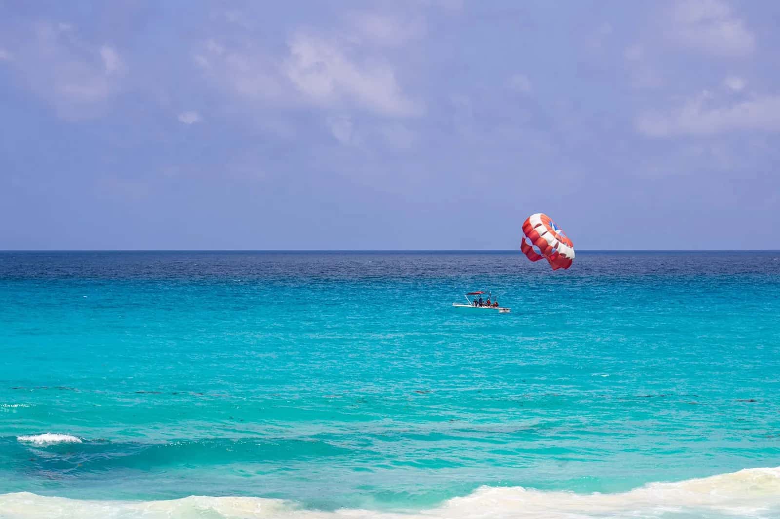 Parachute ascensionnel tracté par un bateau au-dessus du lagon turquoise de l'Île aux Cerfs, île Maurice