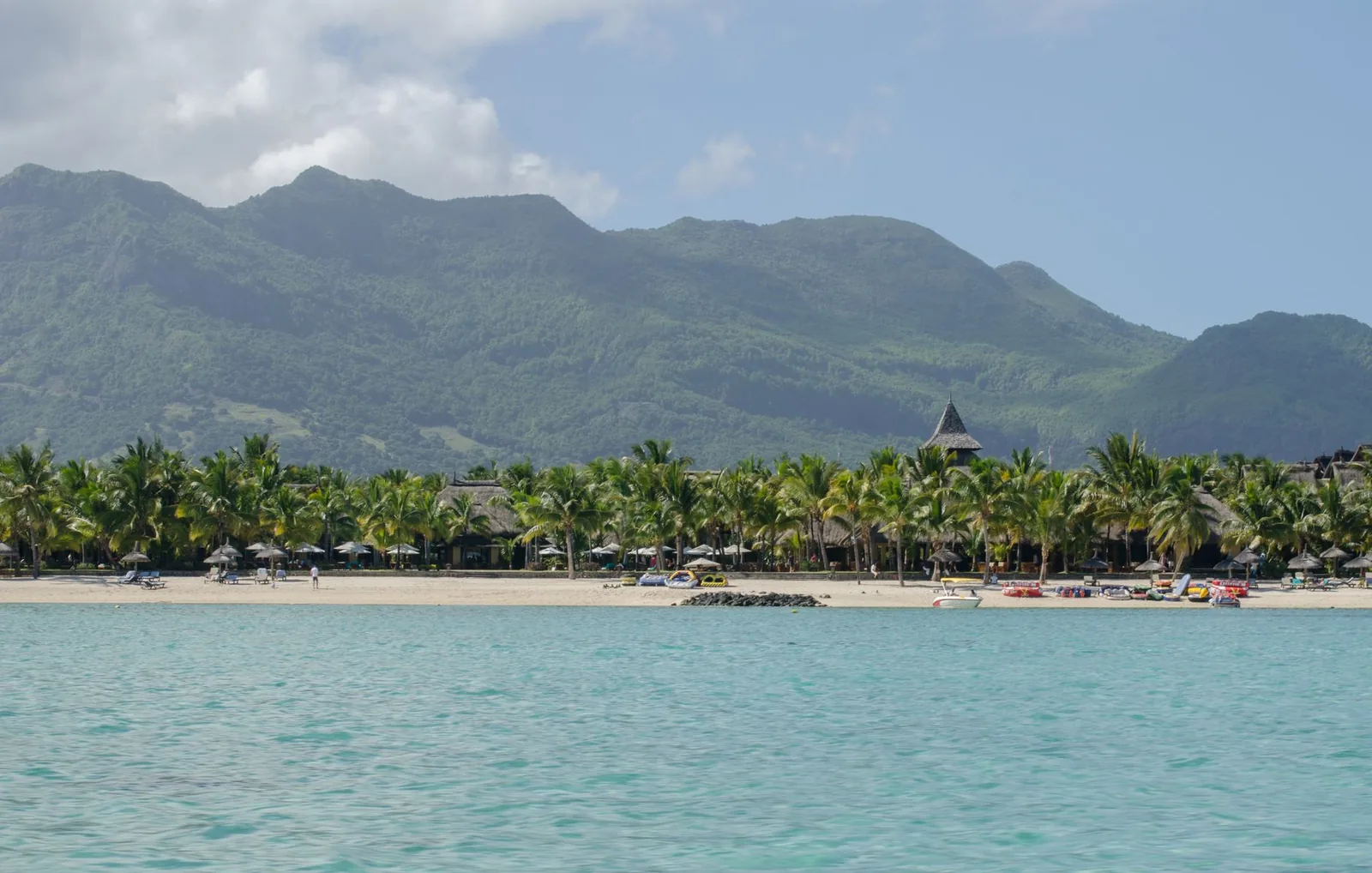Lagon turquoise bordé de cocotiers et plage de sable, montagnes vertes en arrière-plan, sud de l'île Maurice