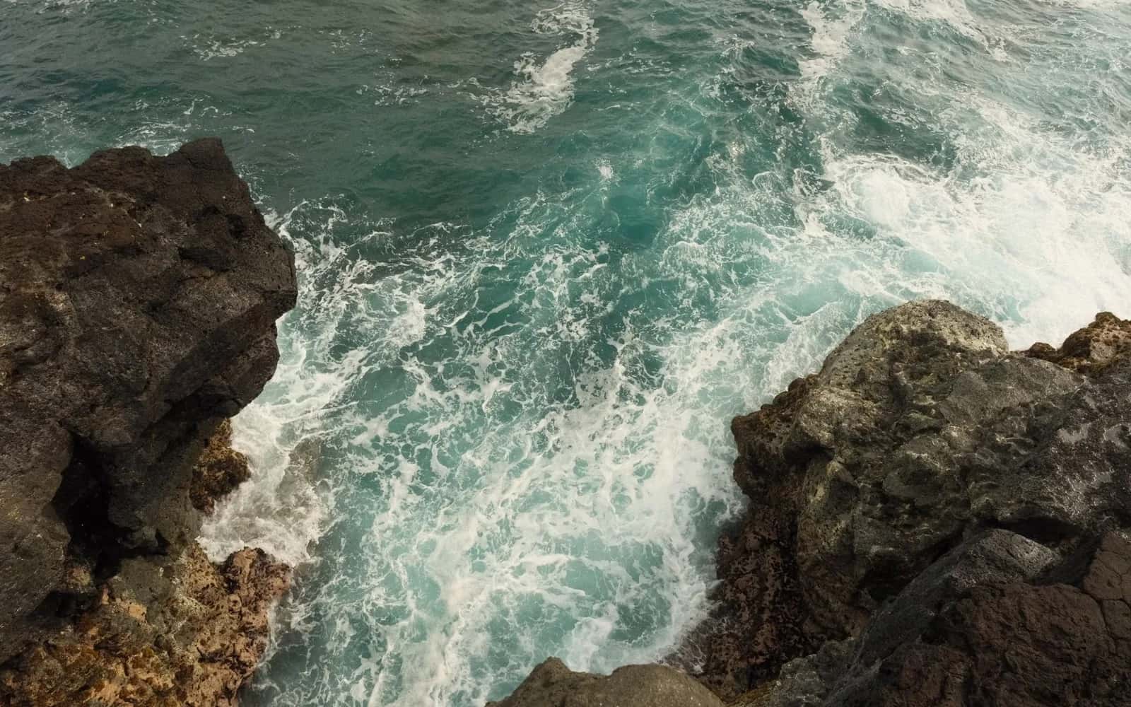 Vagues qui se brisent en gerbes d'écume contre des rochers de lave noire sur la côte sauvage du sud de Maurice