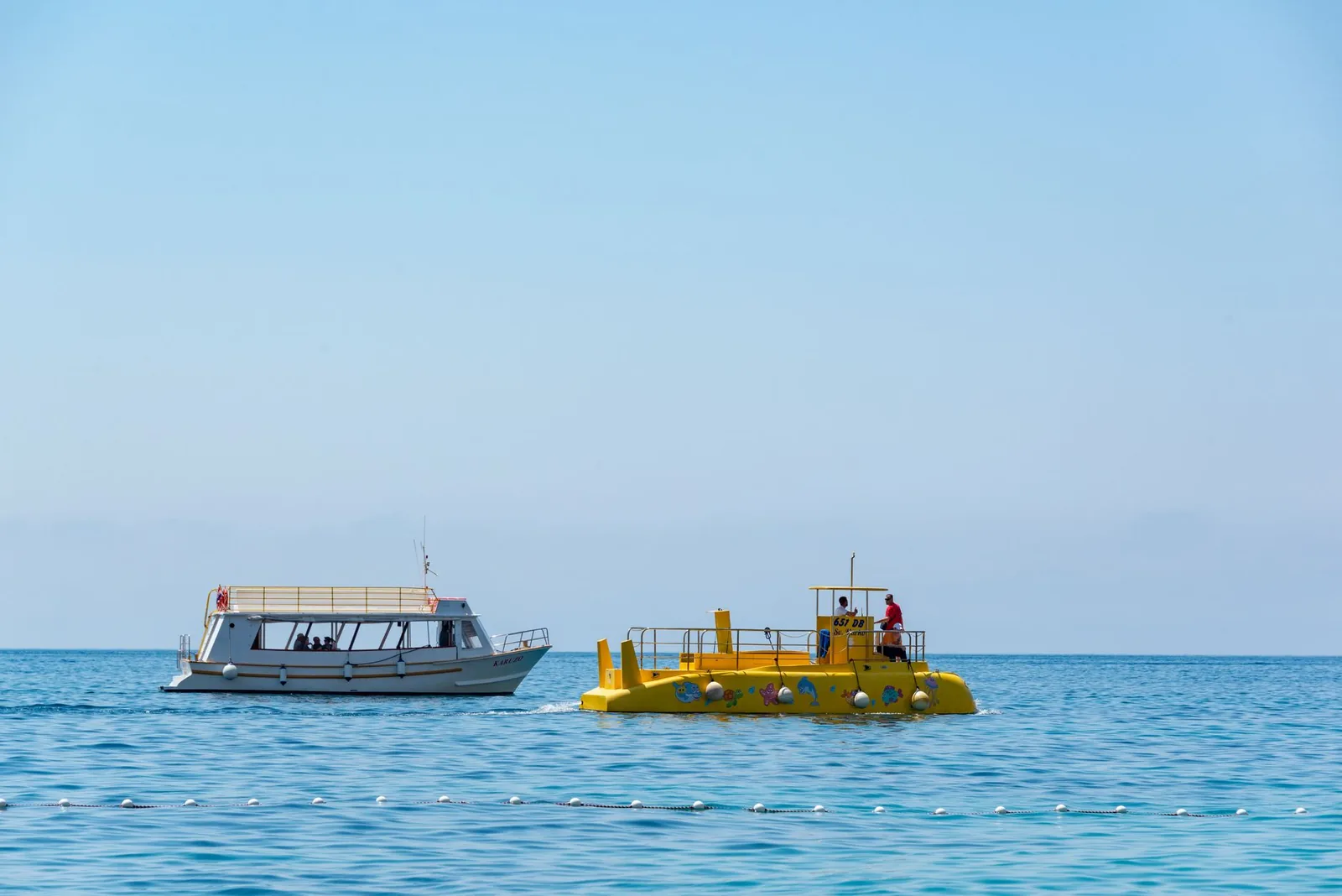 Sous-marin touristique jaune en mer, à côté d'un bateau